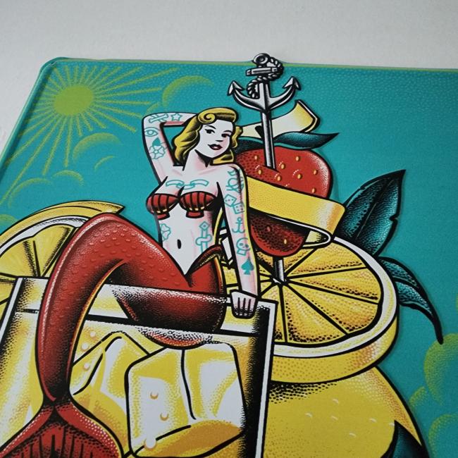 A vibrant Canned Cocktails Tin Tacker from Merchtank, featuring a tattooed mermaid on a glass with ice, lemon slices, and a strawberry—ideal nautical wall decor for any space.
