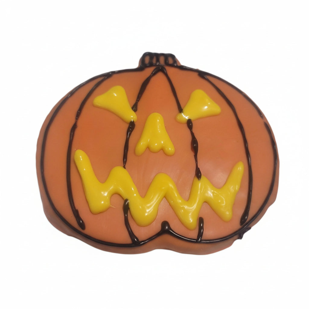 pumpkin iced dog cookie shape with orange icing and yellow pumpkin eyes on white paper.