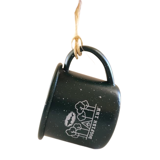 Green mug ornament with a brown string on the handle to hang. Mug features white imagery of trees and a Dogfish Head shark and shield logo, below all is writing "Dogfish Inn".