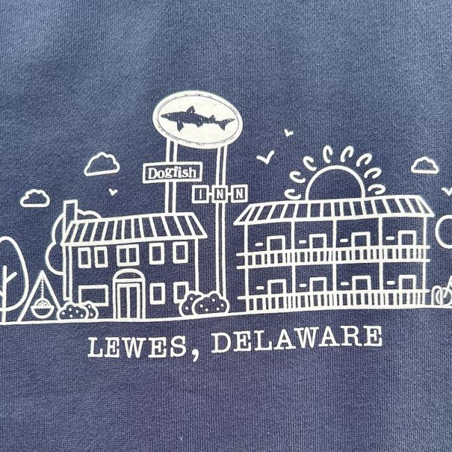 A line drawing on a blue background shows two buildings, a Dogfish Inn sign, trees, and the sun with "LEWES, DELAWARE"—perfect for the GO WEST T-SHIRT COMPANY INN Logo Blue Hoodie or as a souvenir sweatshirt.