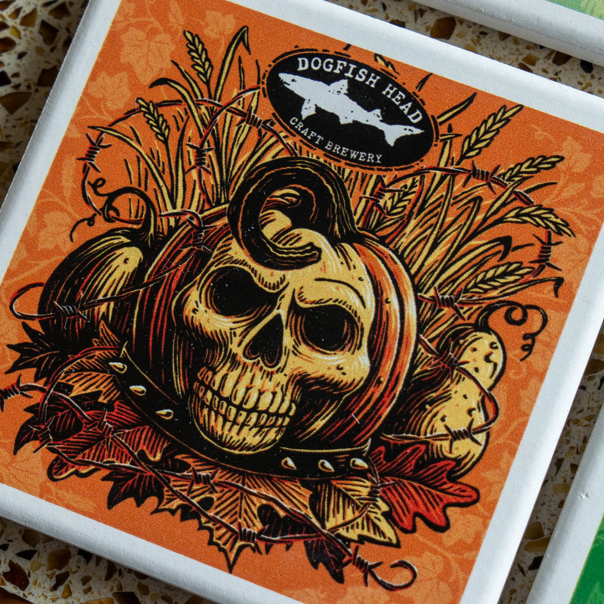 Season-Ale Artist Series Coaster Set featuring a square coaster with an illustration of a skull, a pumpkin, wheat, and barbed wire, with the Dogfish Head craft brewery logo at the top.