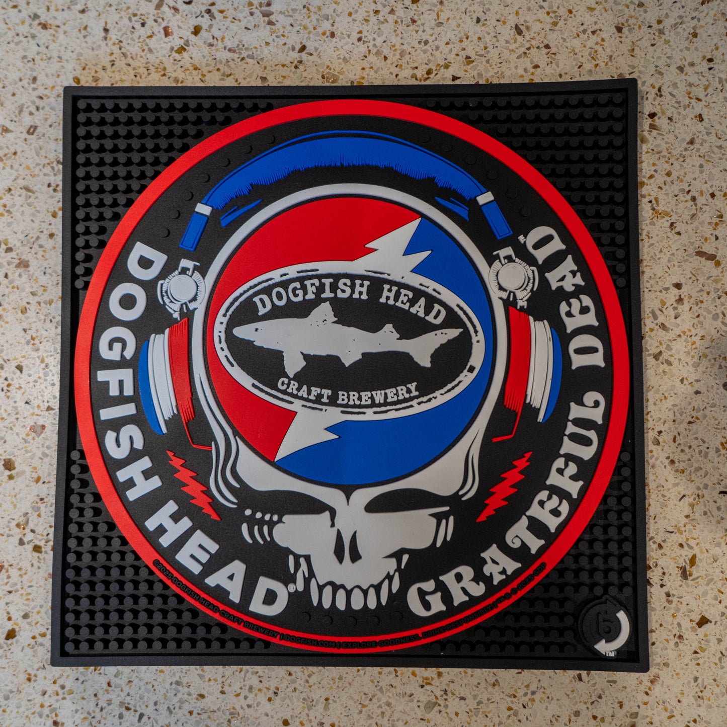Black square bar mat with a red, white, and blue Dogfish Head x Grateful Dead Logo, designed in the classic Grateful dead skull.
