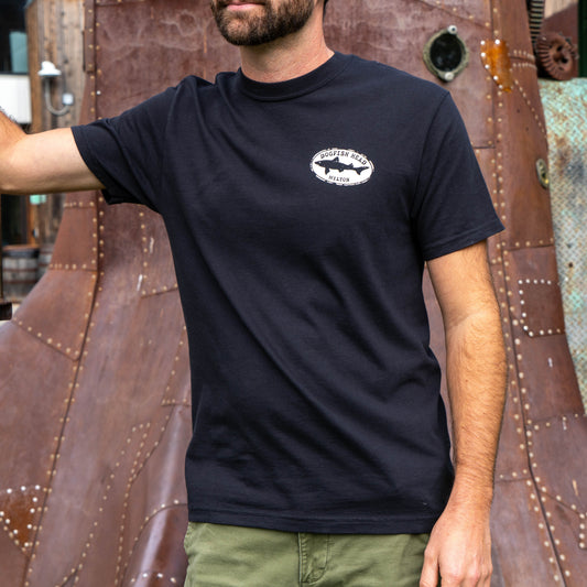 Male standing with arm outward. Wearing black tee shirt that says 'dogfish head Milton'