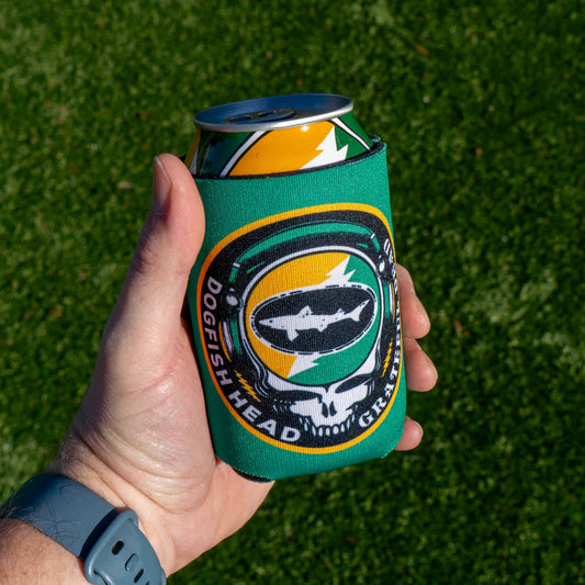 A hand wearing a gray watch holds a can in the Dogfish Head x Grateful Dead Citrus Daydream 12oz Can Cooler by Grandstand Glassware & Apparel, with green grass in the background.