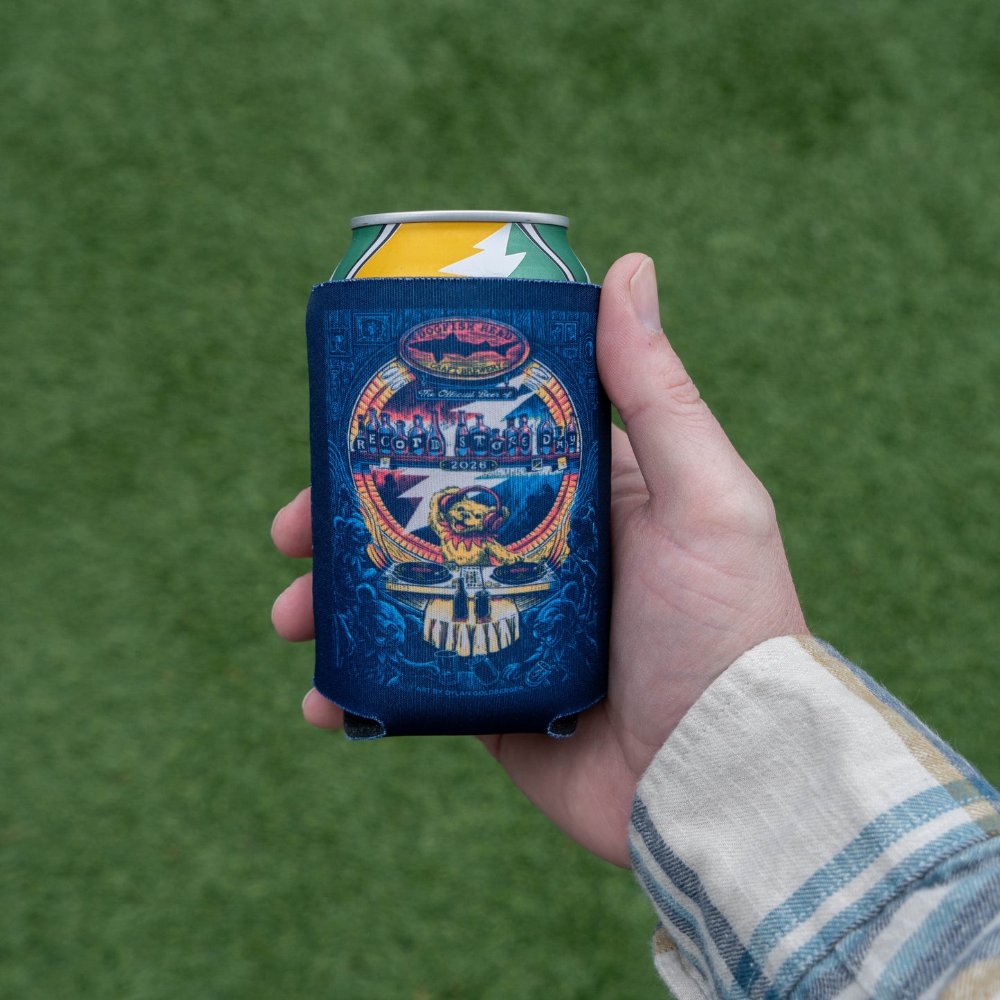 Hand holding a Dogfish Head x Grateful Dead RSD can cooler outdoors, highlighting vibrant illustrated grateful dead bar DJ artwork on the insulated sleeve