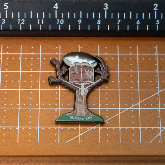 Treehouse Enamel Magnet shaped like a treehouse with a shark silhouette in the sky, labeled Milton DE at the base.
