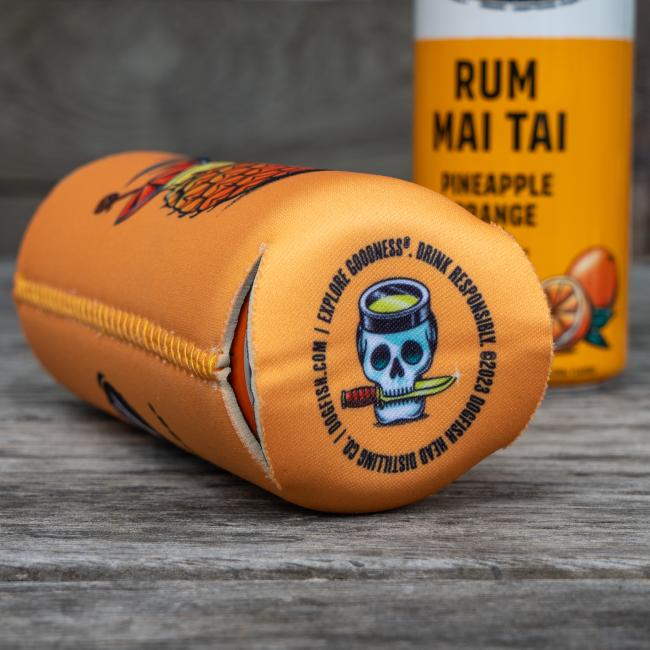 A Peach Pineapple Slim Can Cooler by Merchtank with a cartoon skull and bamboo at the end sits next to a Rum Mai Tai Pineapple Orange can on a wooden surface.