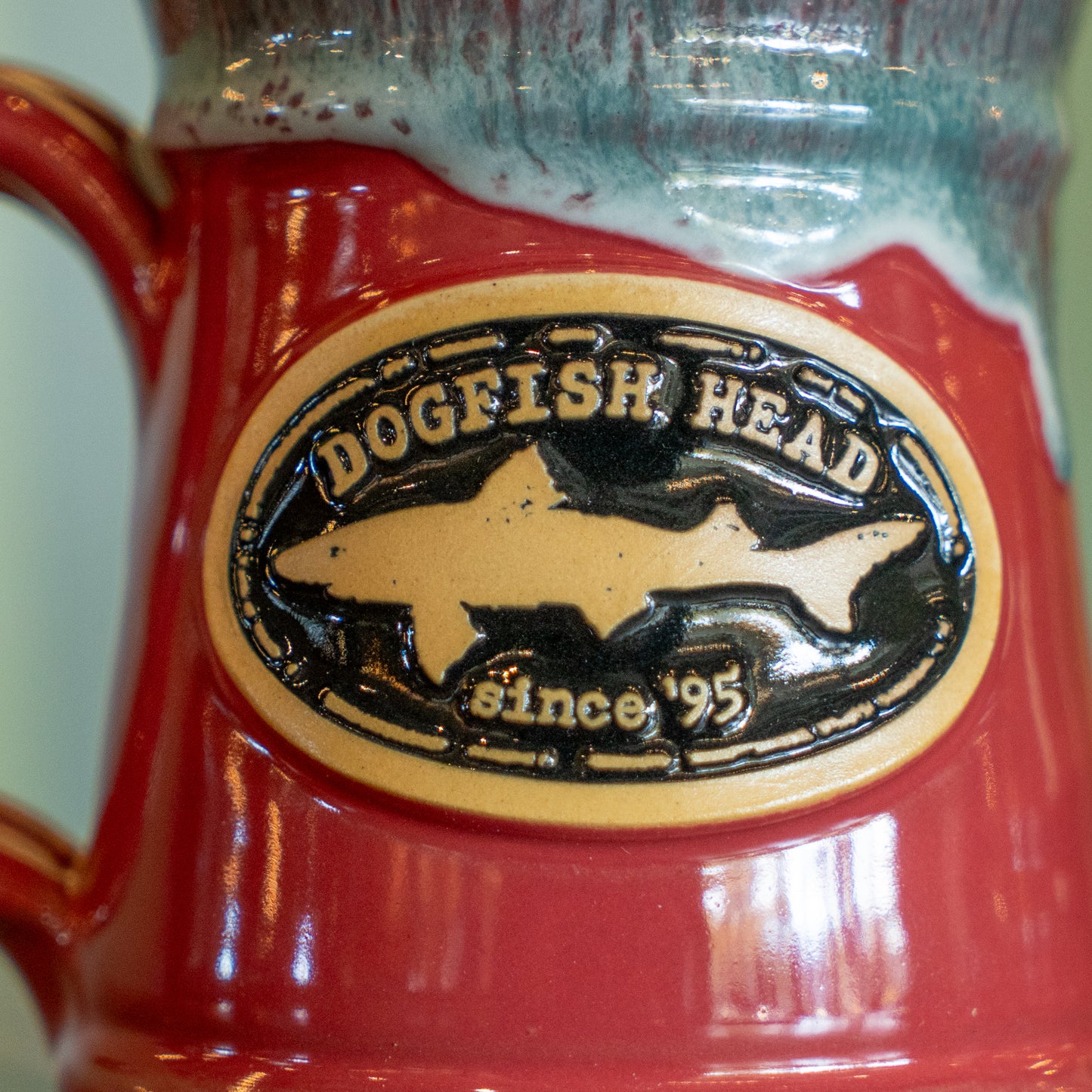 A close-up of a pink ceramic Splitrock mug by Deneen Pottery, featuring an oval badge—perfect for showing off your brand pride.