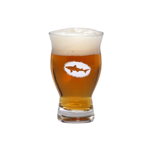 A Grandstand Glassware & Apparel 5oz Revival Tasting Glass filled with golden amber beer and a thick, foamy head, featuring the logo with a shark in an oval on the front. The glass is set against a plain white background.