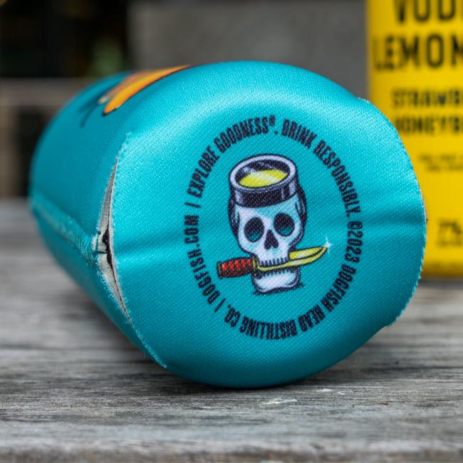 The bottom of the blue can cooler with a skull graphic with a red knife in its mouth. Text on the can says "Explore Goodness. Drink Responsibly." for refreshing style.