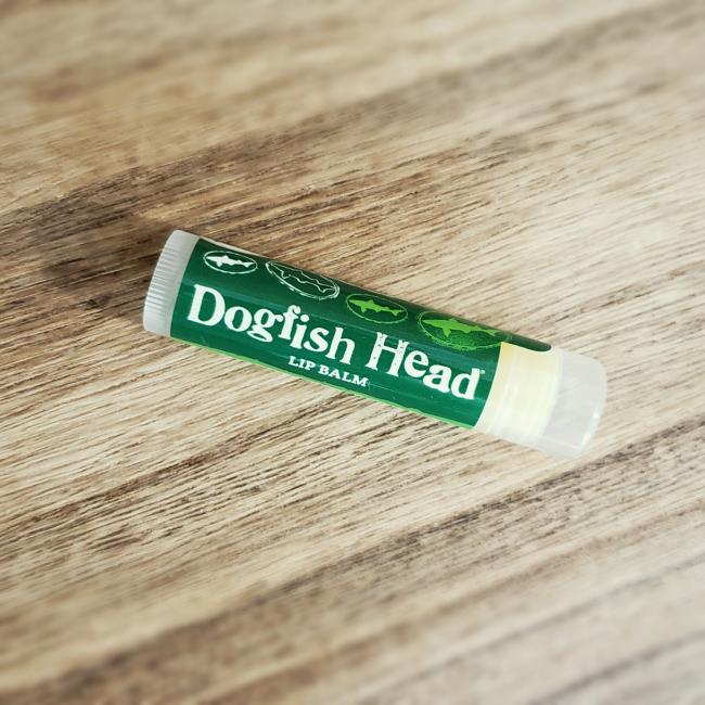 A tube of DFH Lip Balm by Eco Lips Inc, with a green label displaying the brand name, rests on a wooden surface.