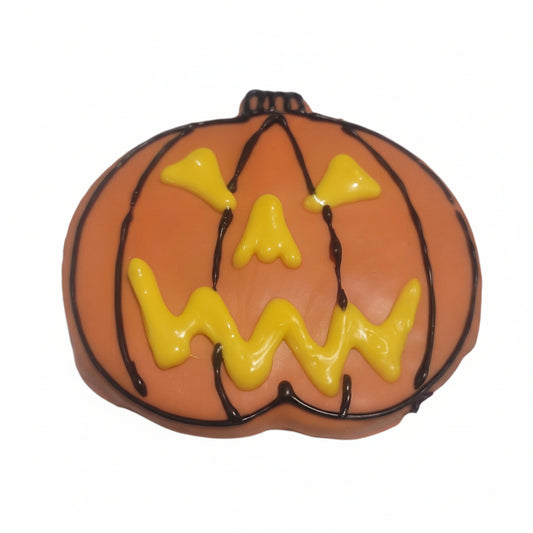 pumpkin iced dog cookie shape with orange icing and yellow pumpkin eyes on white paper.