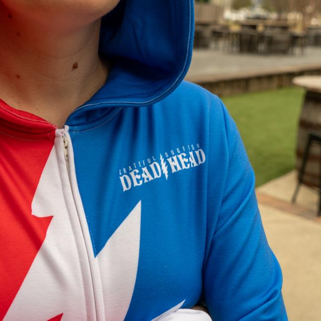 A person wearing the Dogfish Head x Grateful Dead Adult Onesie by In Your Face Apparel, inspired by Grateful Dead style. The outdoor photo captures only part of their face and upper body.