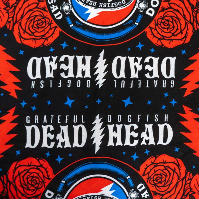 The Merchtank Dogfish Head x Grateful Dead Bandana features a red, black, and blue design with roses, lightning bolts, stars, and mirrored "Grateful Dogfish Dead Head" text—great for any craft beer accessory collection.