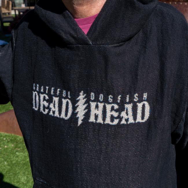 Someone is wearing a Dogfish Head x Grateful Dead Fiber Art Hoodie by Pure Country Inc - Fiber Art, featuring "Grateful Dogfish Dead Head" with a lightning bolt design. Only the torso and part of the head are visible.