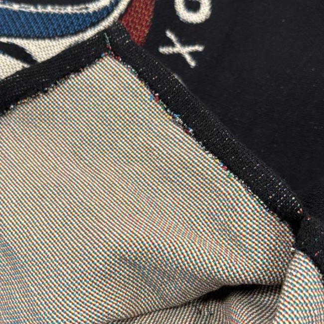 Close-up of the Dogfish Head x Grateful Dead Fiber Art Hoodie by Pure Country Inc - Fiber Art, showing woven cotton fabric, inside stitching, and hem. Visible threads reveal part of an embroidered red, white, and blue design on the outside.