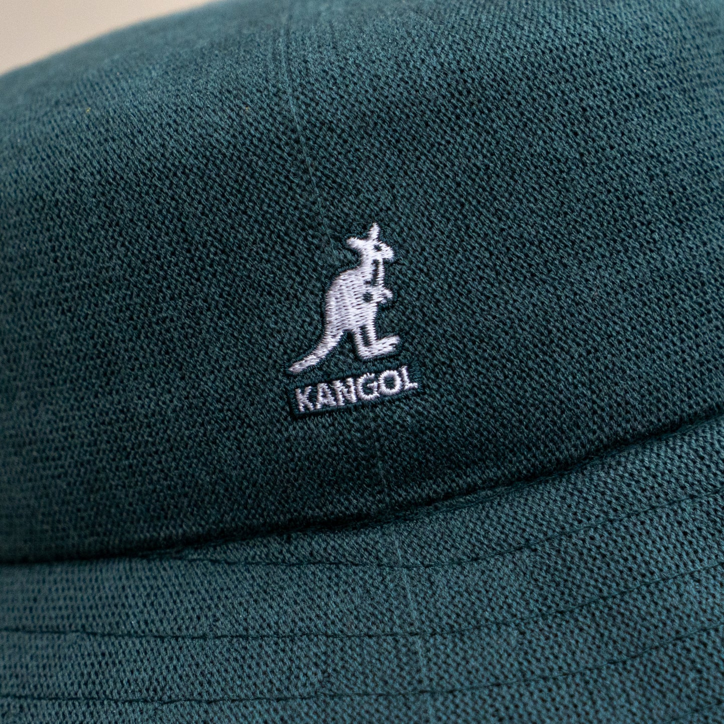 Close-up of the Dogfish Head x Grateful Dead KANGOL Bucket Hat by BOLLMAN HATS, green with a white kangaroo logo and KANGOL text embroidered on the fabric.