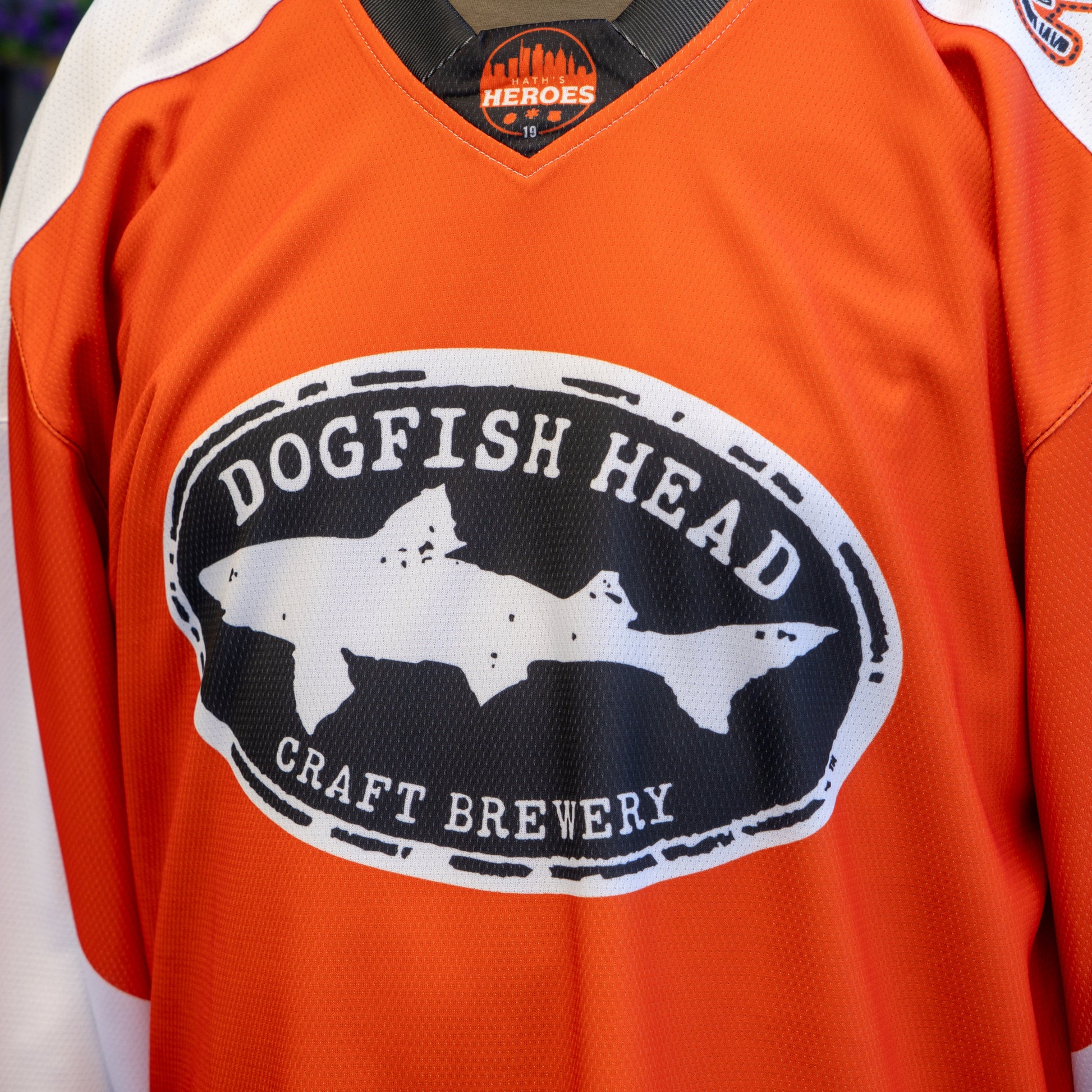 A close-up of the Dogfish Head x Garnet Hathaway Engine 19 Hockey Jersey by In Your Face Apparel, featuring the black and white Dogfish Head Craft Brewery logo—a standout from this dynamic collaboration.