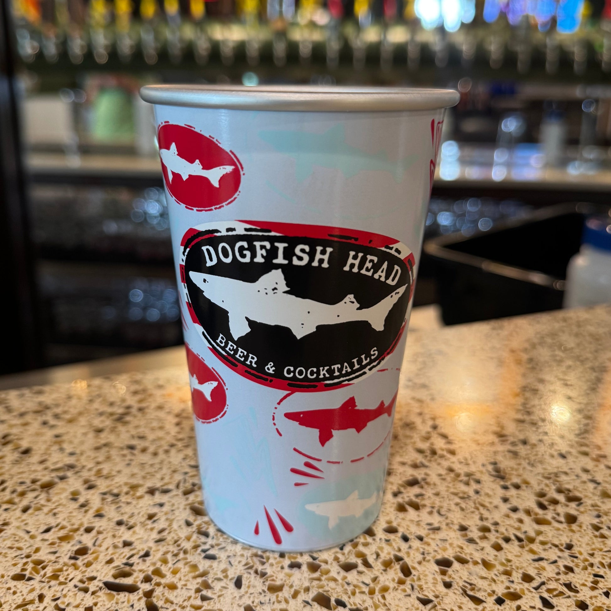 Dogfish Head aluminum can style reusable pint glass with shark logo design, lightweight eco-friendly drinkware on bar counter in taproom setting