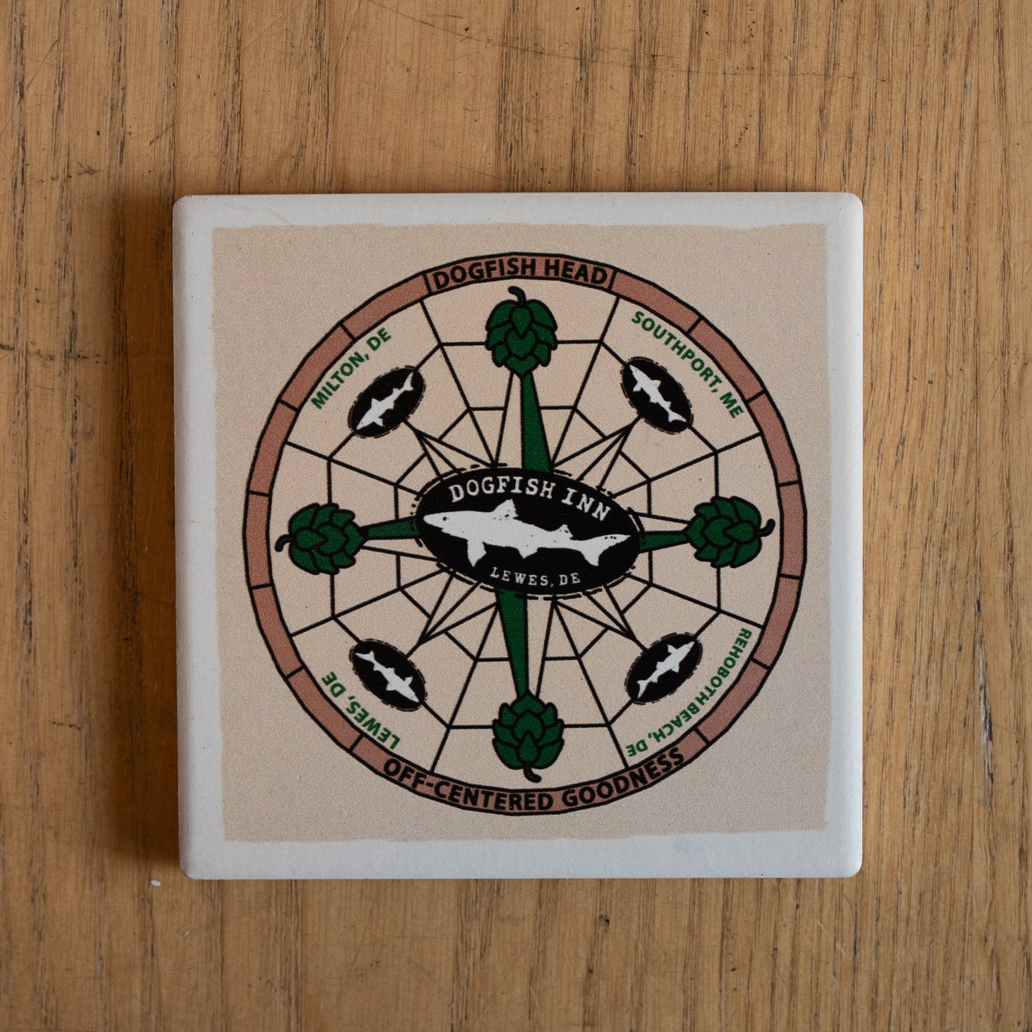 The Inn Ceramic Off Centered Coaster by Paint the Town, Inc. features a compass rose design and "Dogfish Head Inn, Lewes, DE" in the center—celebrating your craft journey as the perfect pint companion.