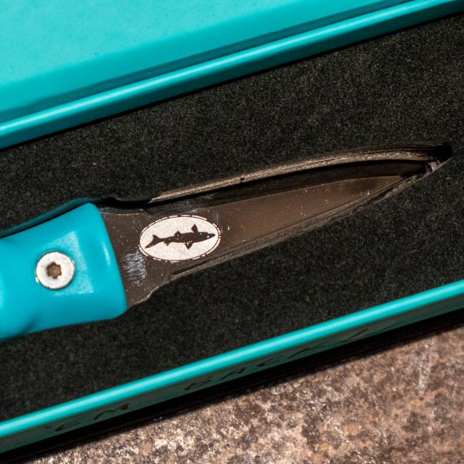 Blue oyster knife features the Dogfish Head shark and shield logo engraved on one side of the knife. The other side of the knife features the Toadfish logo engraved. 