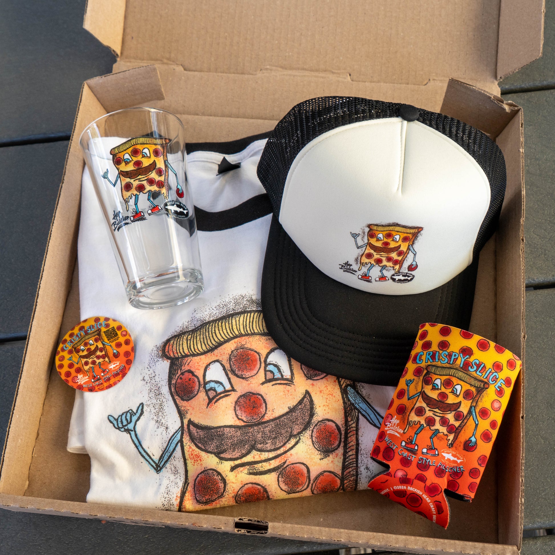 The Crispy Slice Merch Bundle by GO WEST T-SHIRT COMPANY features a pizza tee, black and white trucker hat, pint glass, button, and can cooler—each with a cartoon pizza slice character with mustache and arms.