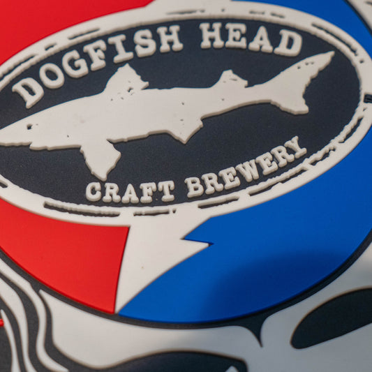 Close up of black square bar mat with a red, white, and blue Dogfish Head x Grateful Dead Logo.