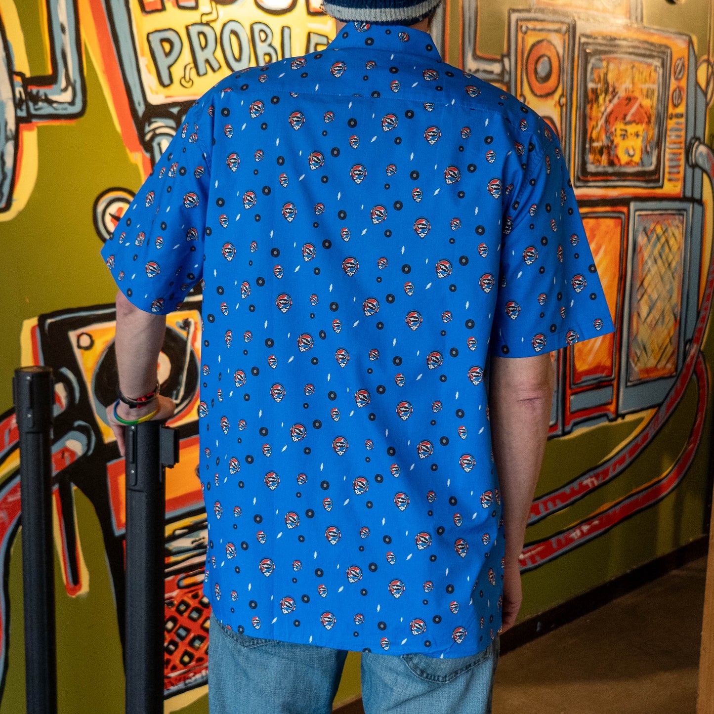 Backside of blue Dogfish Head x Grateful Dead button-down shirt, designed in small lightning bolts, records, and Dogfish Head x Grateful dead red, white, and blue logos.