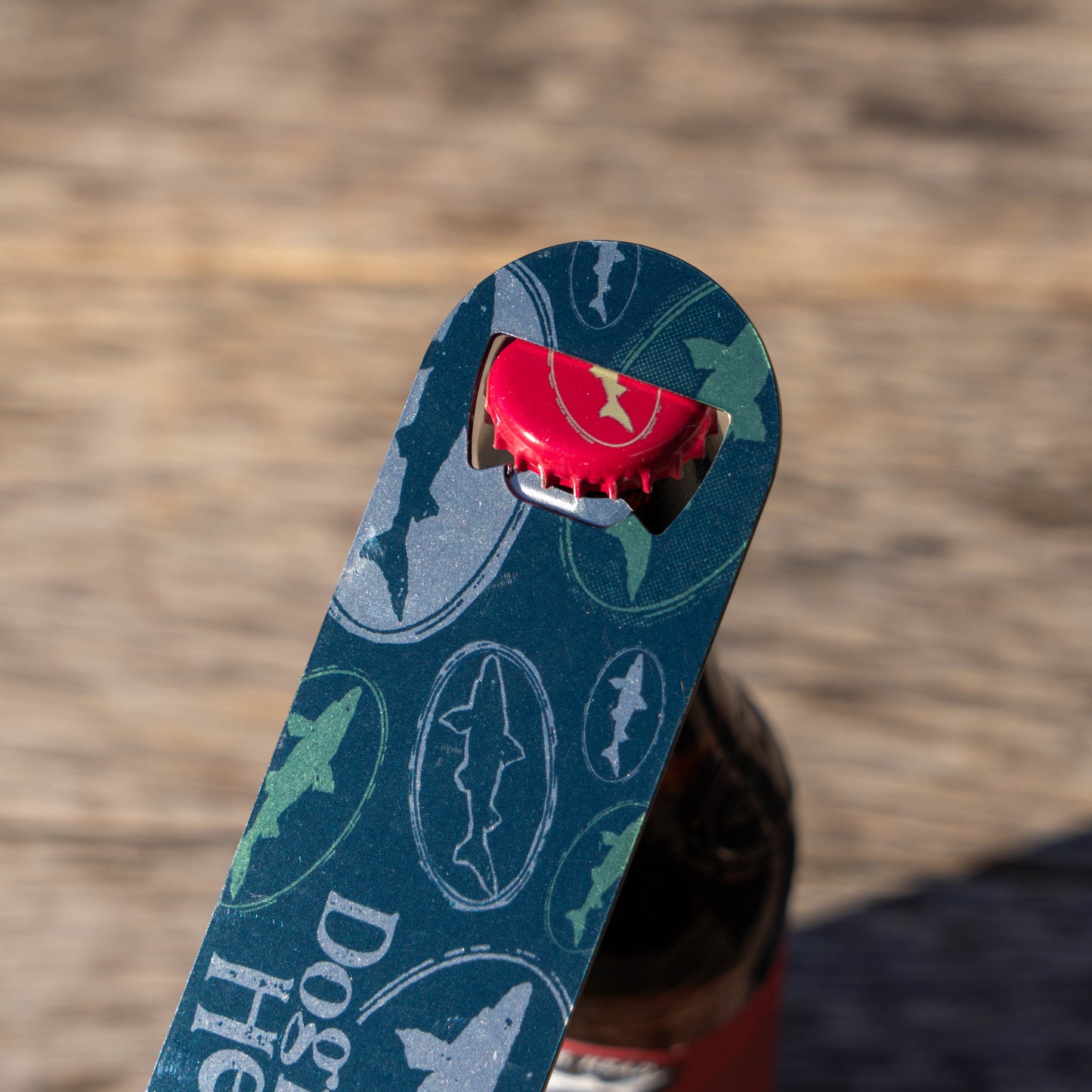 Bottle opener with shark design on a wooden surface