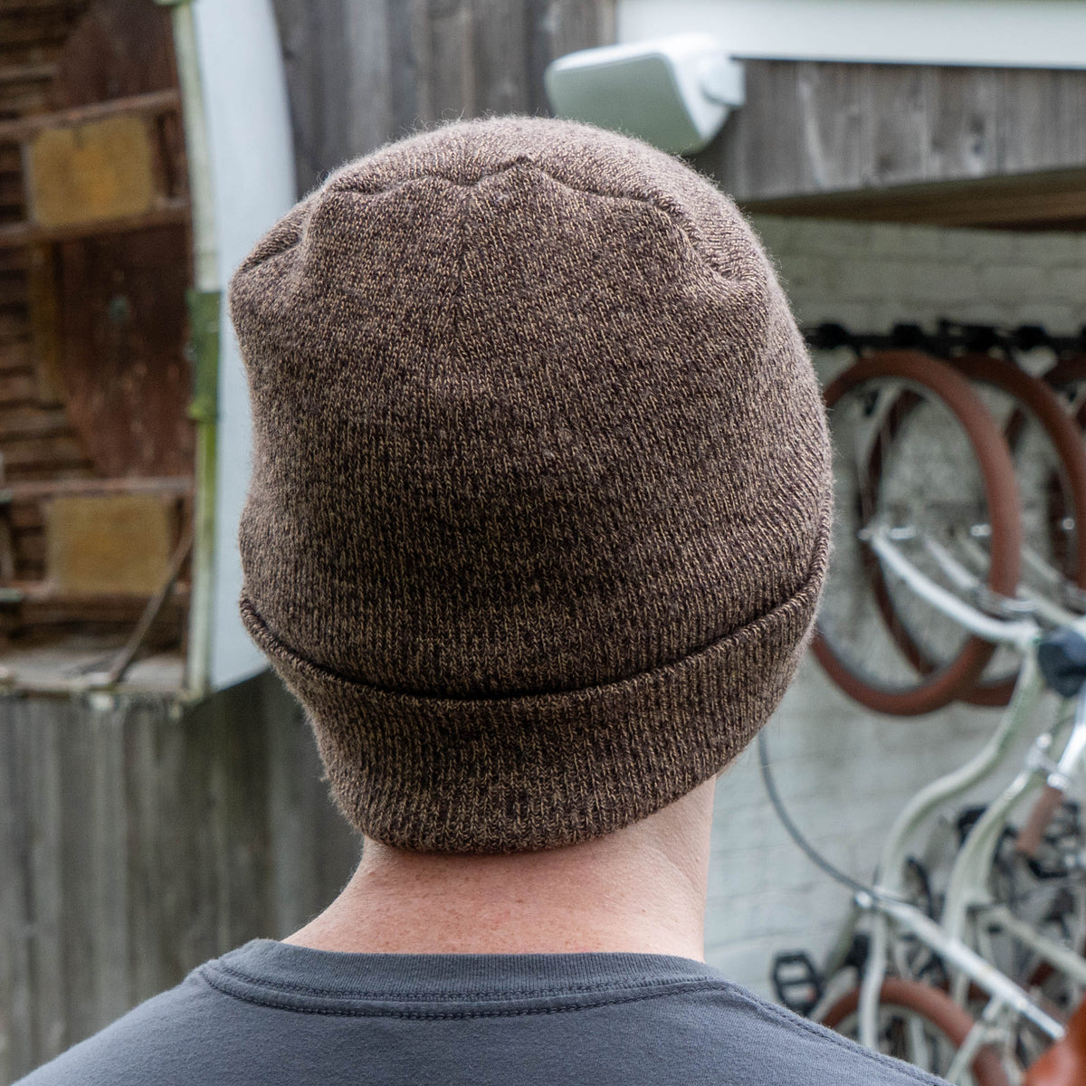 A person wearing a brown marled ARTEX KNITTING MILLS Firepit Beanie with a folded cuff.