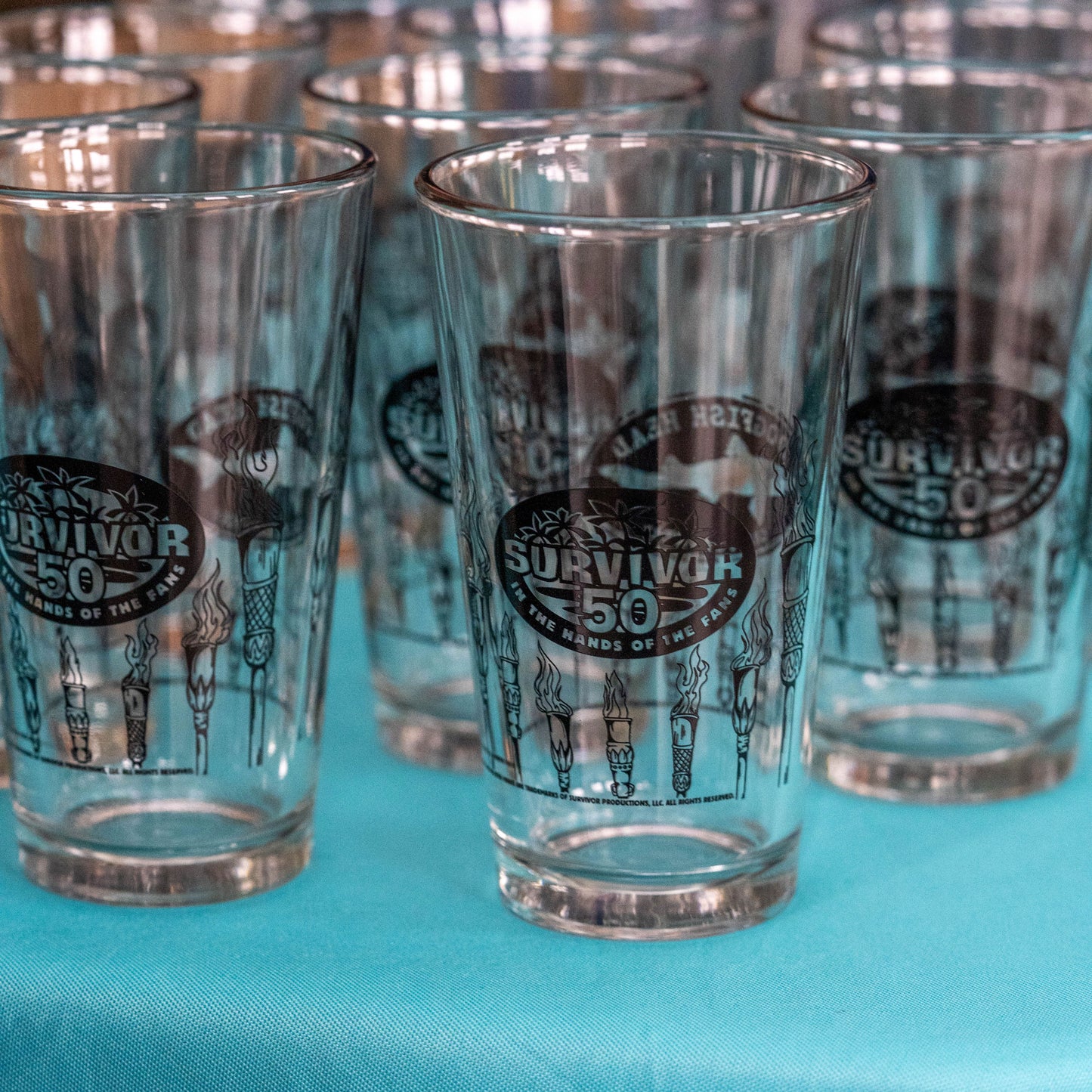 Clear glasses with 'Survivor 50' logo on a blue surface