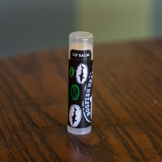 A tube of Eco Lips Inc Lip Balm stands upright on a wooden surface.