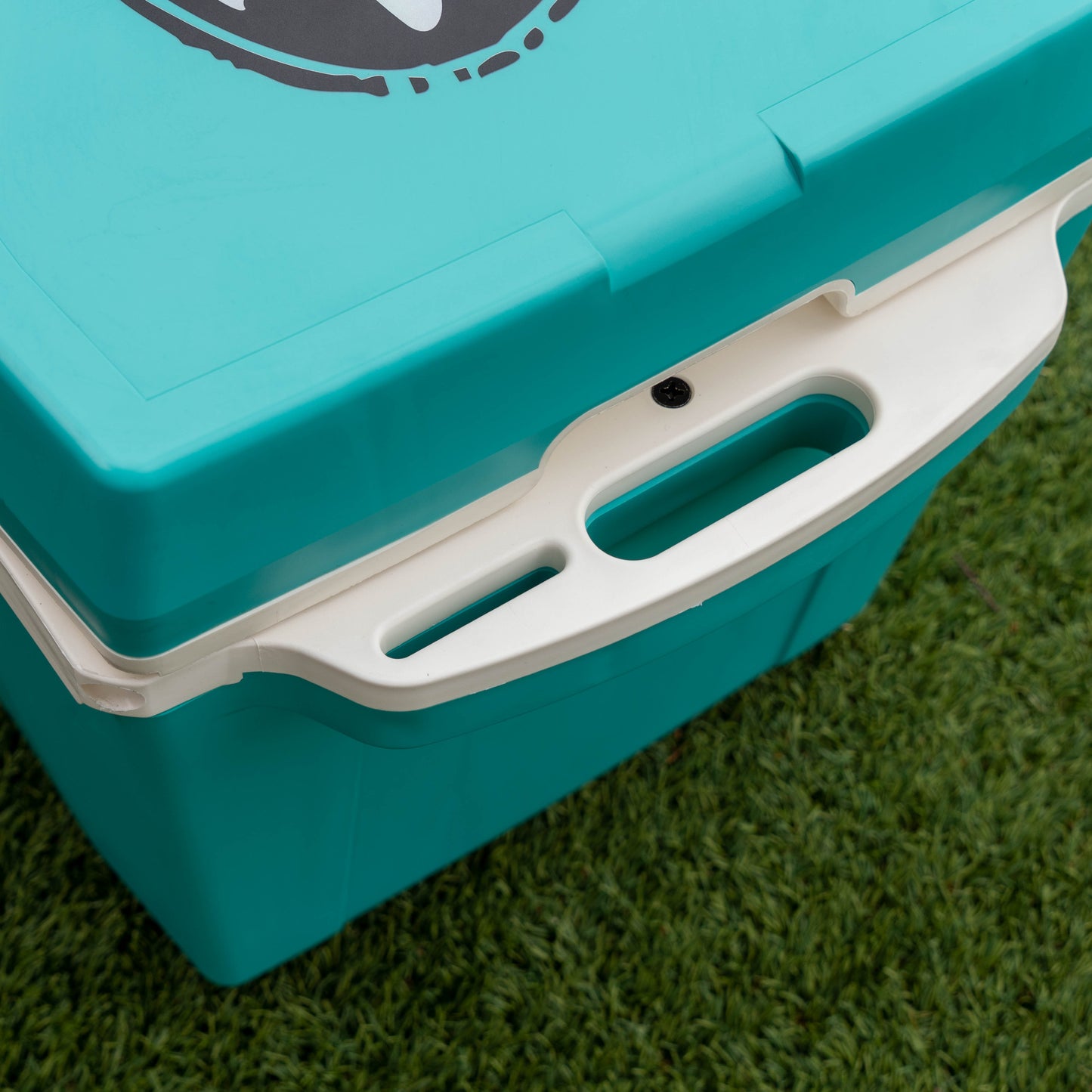Turquoise cooler box with white handle on a grassy background