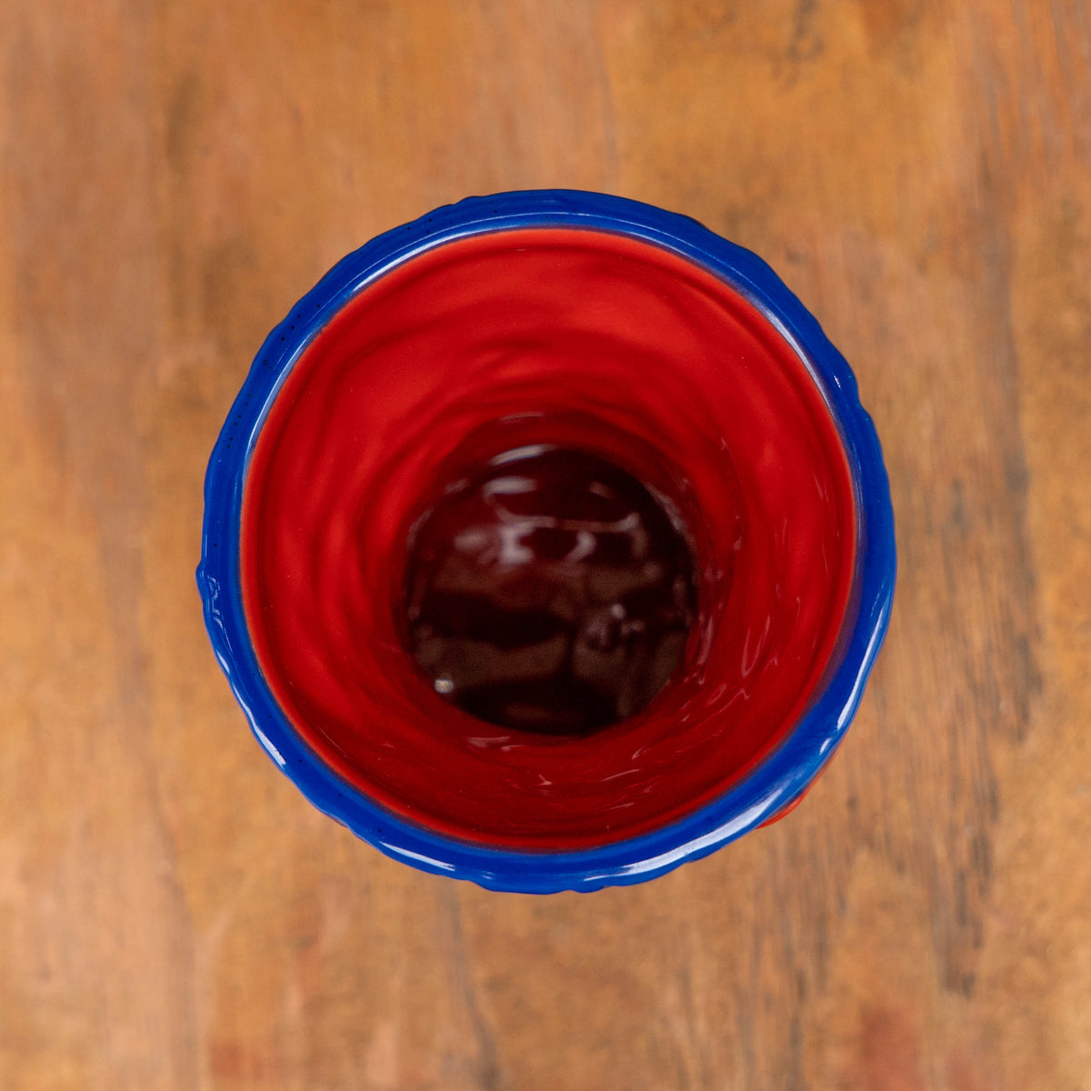 Top-down view into a Dogfish Head x Grateful Dead TIKI FARM Ceramic Mug with a bright red interior and a thick blue rim.