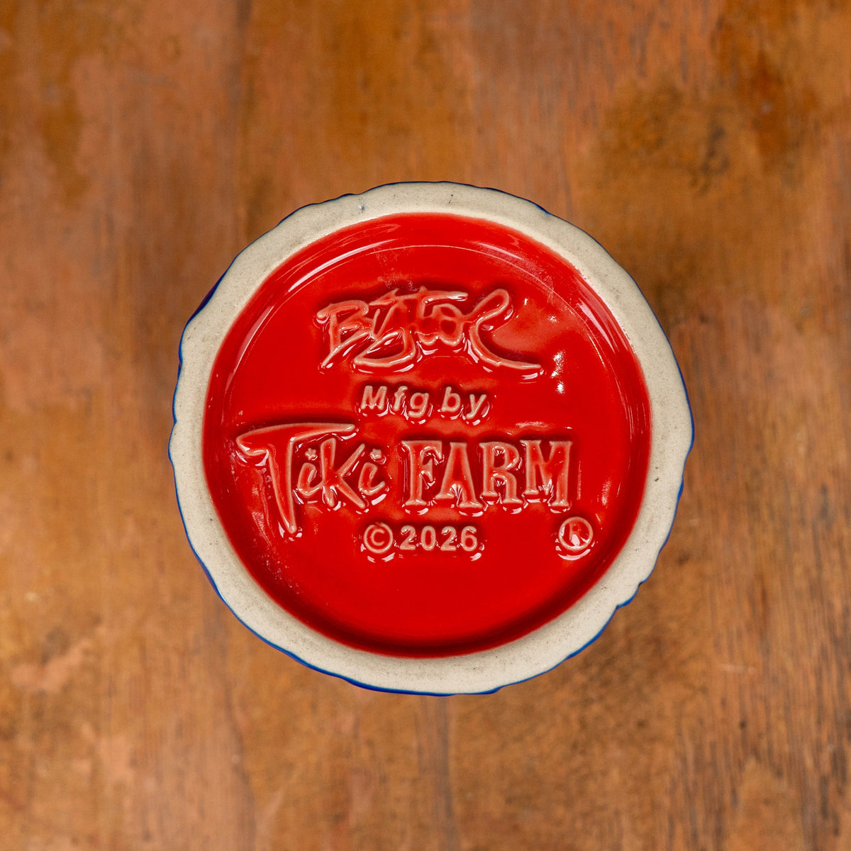 The red underside of a Dogfish Head x Grateful Dead TIKI FARM Ceramic Mug, featuring embossed text that reads Mfg by Tiki Farm and 2026.