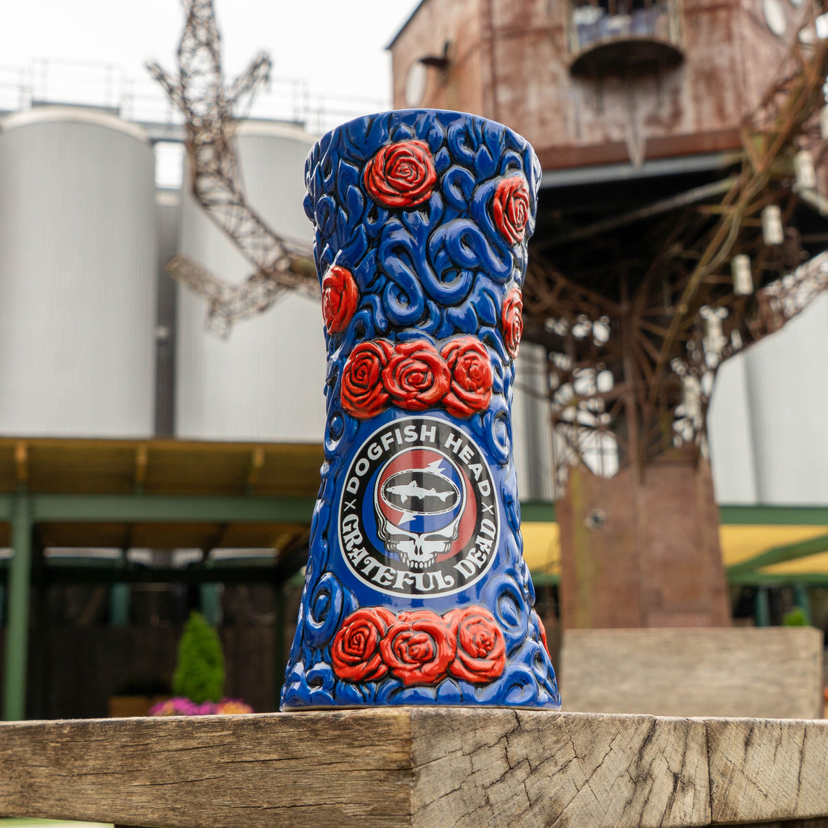 Blue ceramic Dogfish Head x Grateful Dead TIKI FARM Ceramic Mug decorated with red roses and a circular Grateful Dead and Dogfish Head logo.