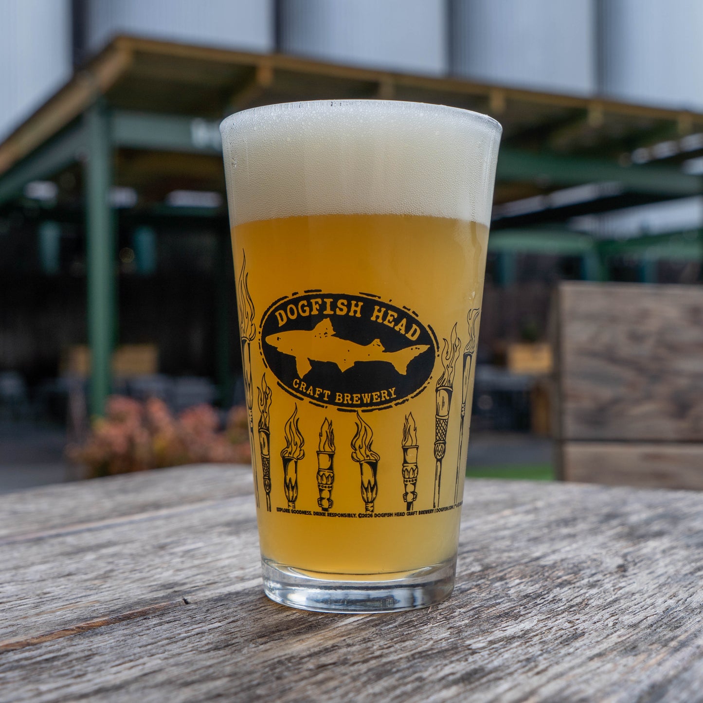 Dogfish Head craft brewery glass of beer on a wooden table with a blurred background