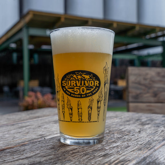 Pint of beer with 'Survivor 50' logo on a wooden surface