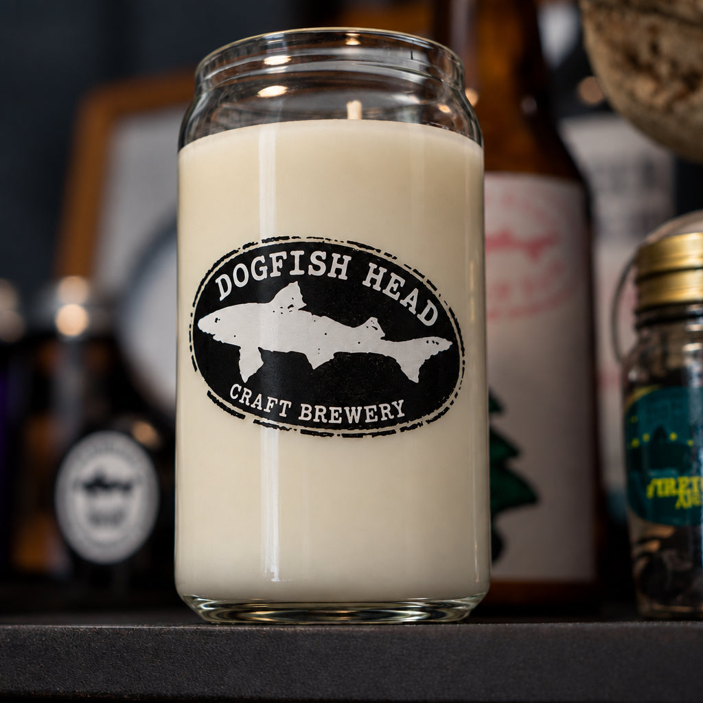 A Delaware Grunge Can Glass Candle filled with cream-colored wax, featuring a black oval logo with a white shark silhouette and the text Dogfish Head Craft Brewery.