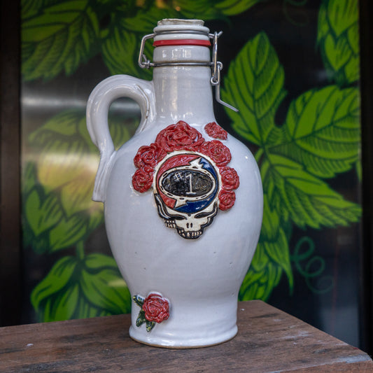 The Uber Growler by Romanick Pottery is a handmade ceramic jug with a handle, adorned with a red rose and Grateful Dead skull logo—a unique holiday gift for any growler fan.
