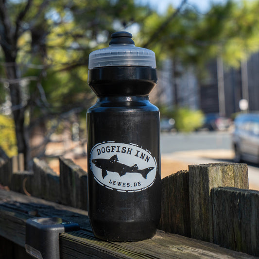 Black water bottle with Dogfish Inn logo on a wooden surface outdoors