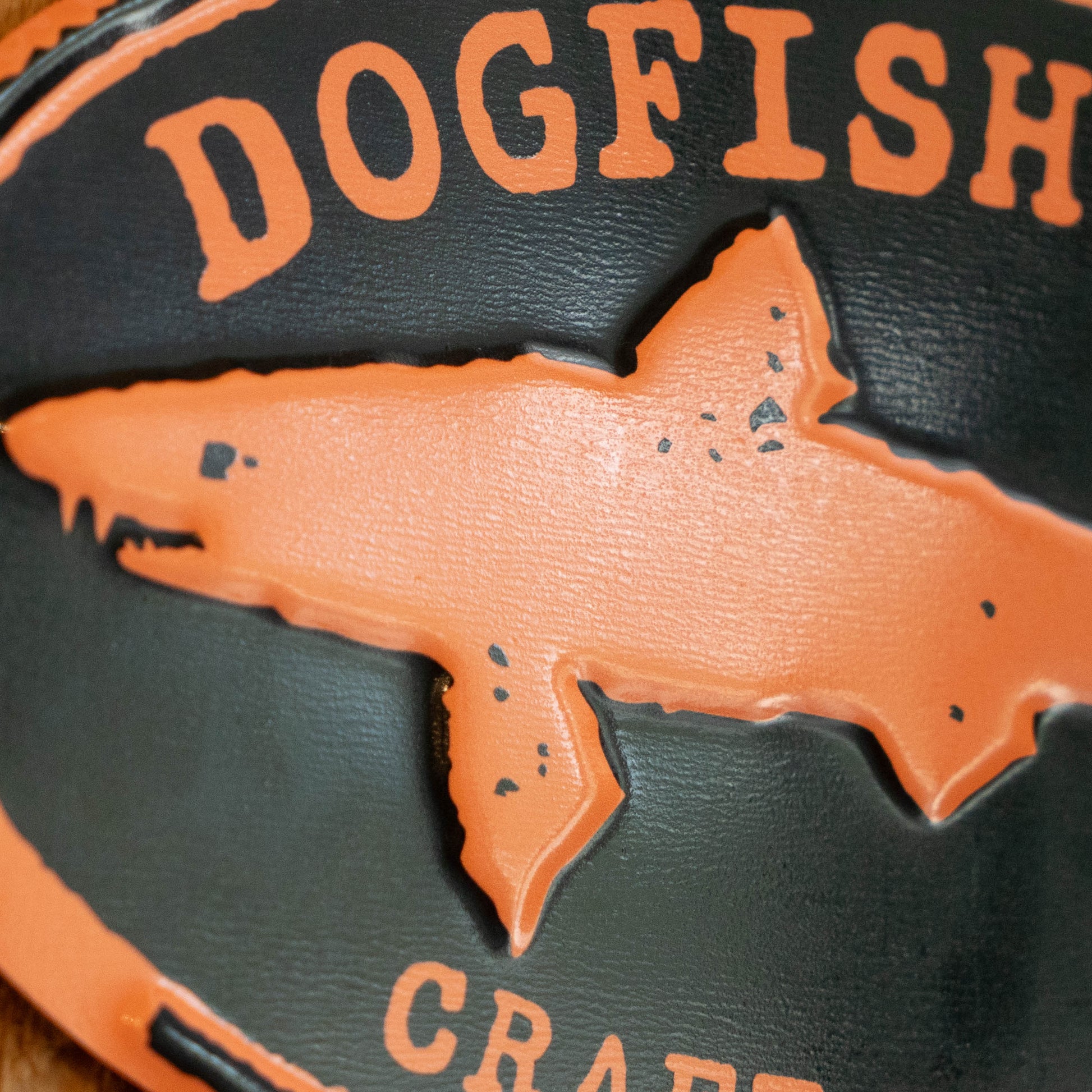 Close-up of a black with orange embossed lettering reading "DOGFISH" and a large orange shark silhouette across the center.