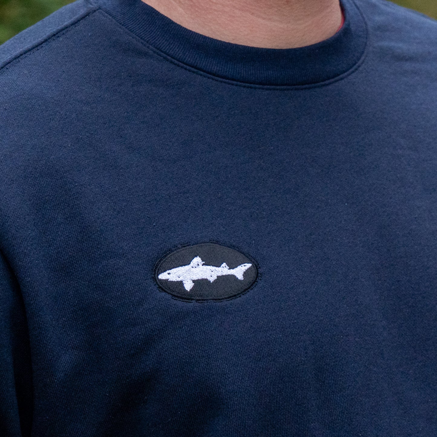 Navy blue sweatshirt with a shark logo on a person wearing it.