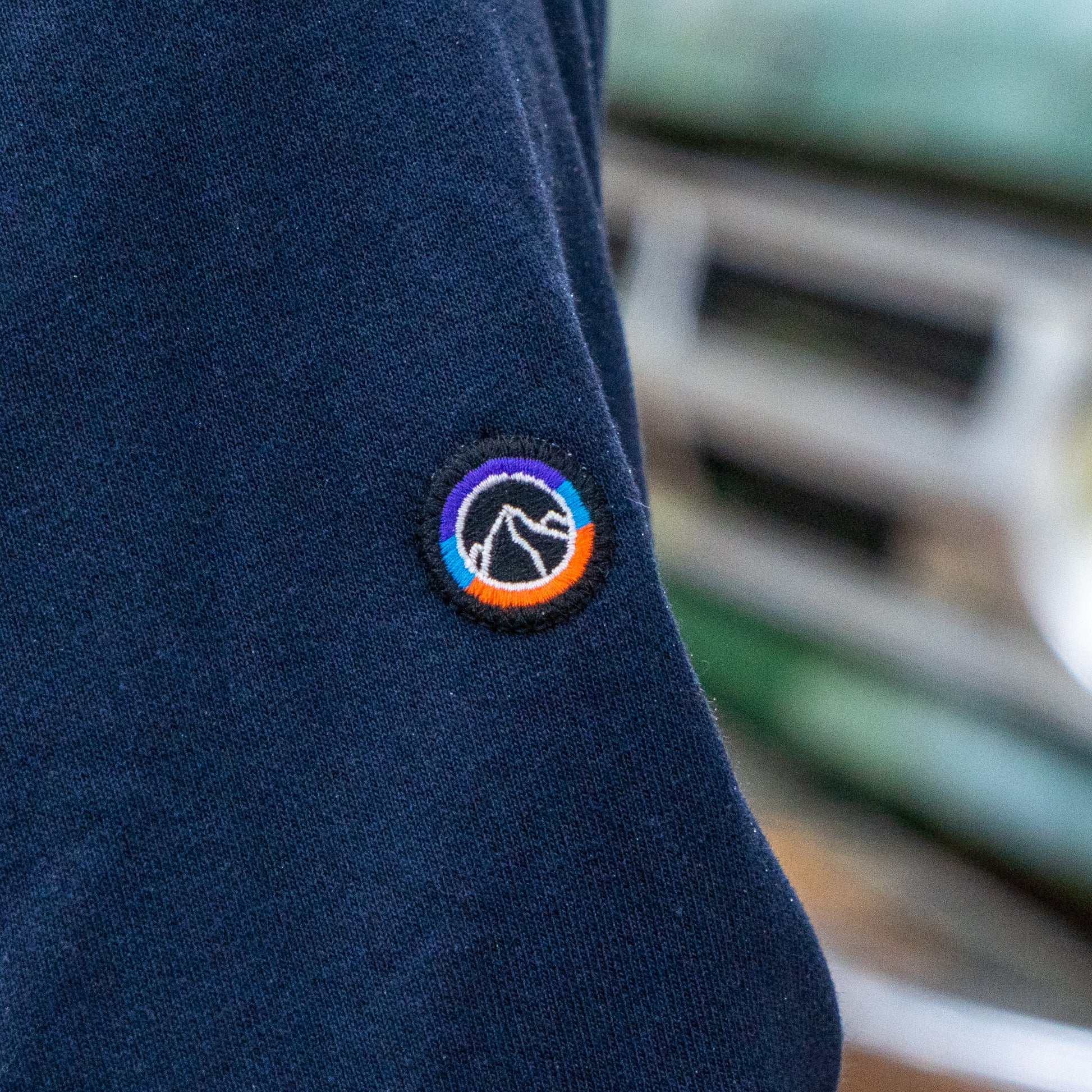Navy blue fabric with a colorful logo patch on a blurred background