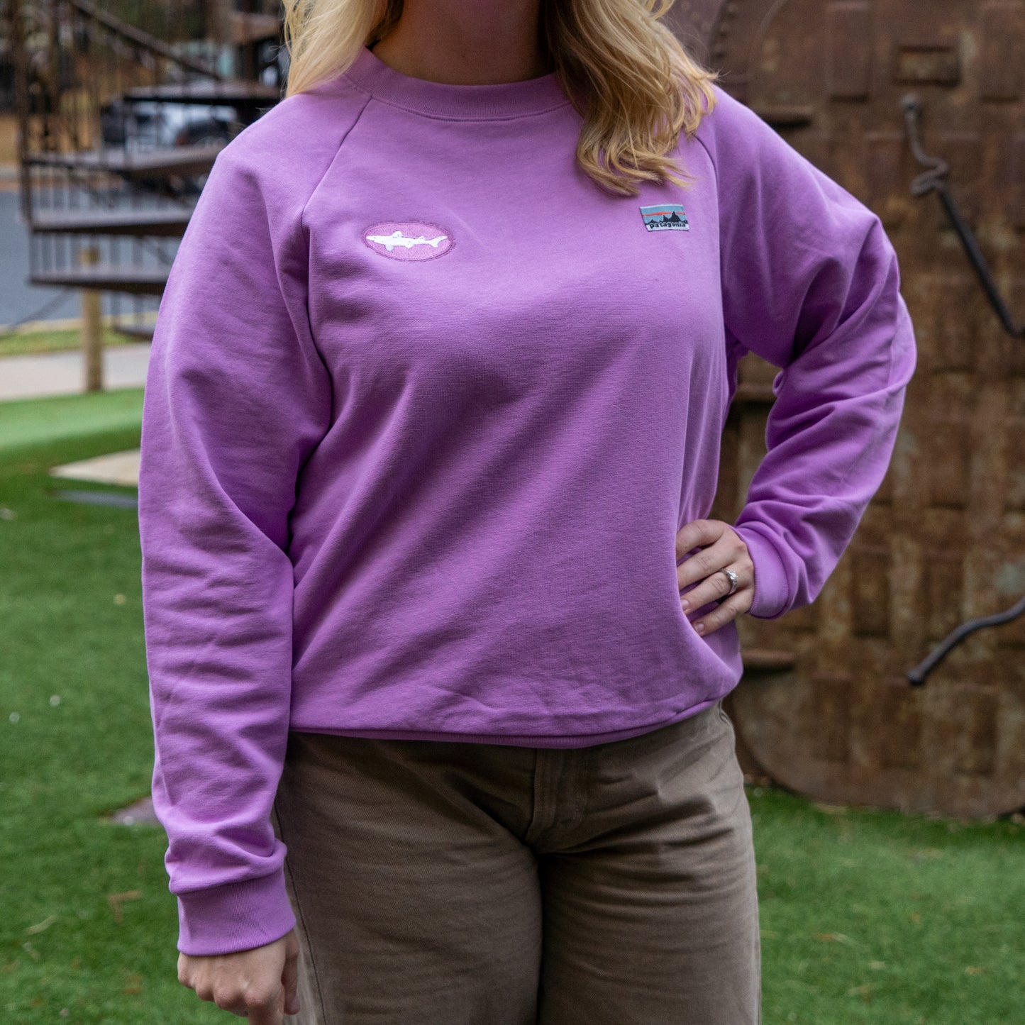 Person wearing a purple sweatshirt with Dogfish Head and Patagonia logos outdoors
