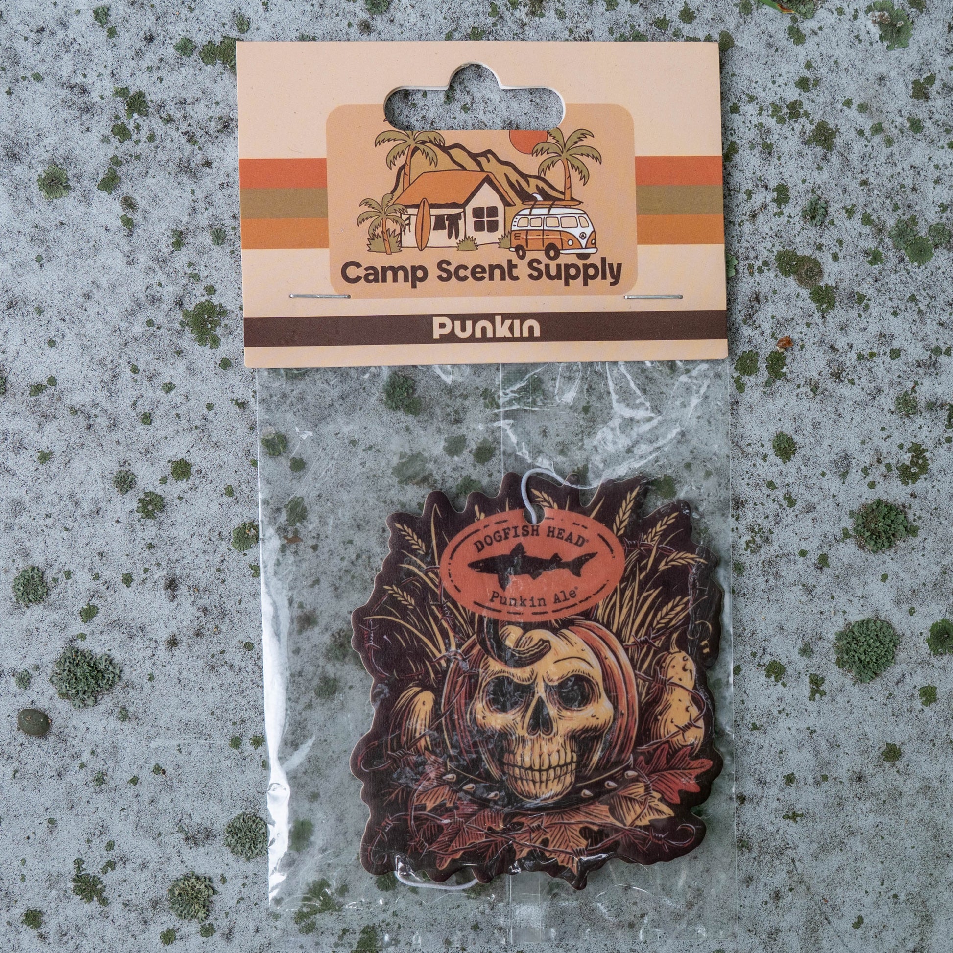 A Punkin camp scent wood plaque by Camp Scent Supply, featuring a skull and shark design, sealed in a clear plastic bag with its cardboard backing card on a textured gray background.