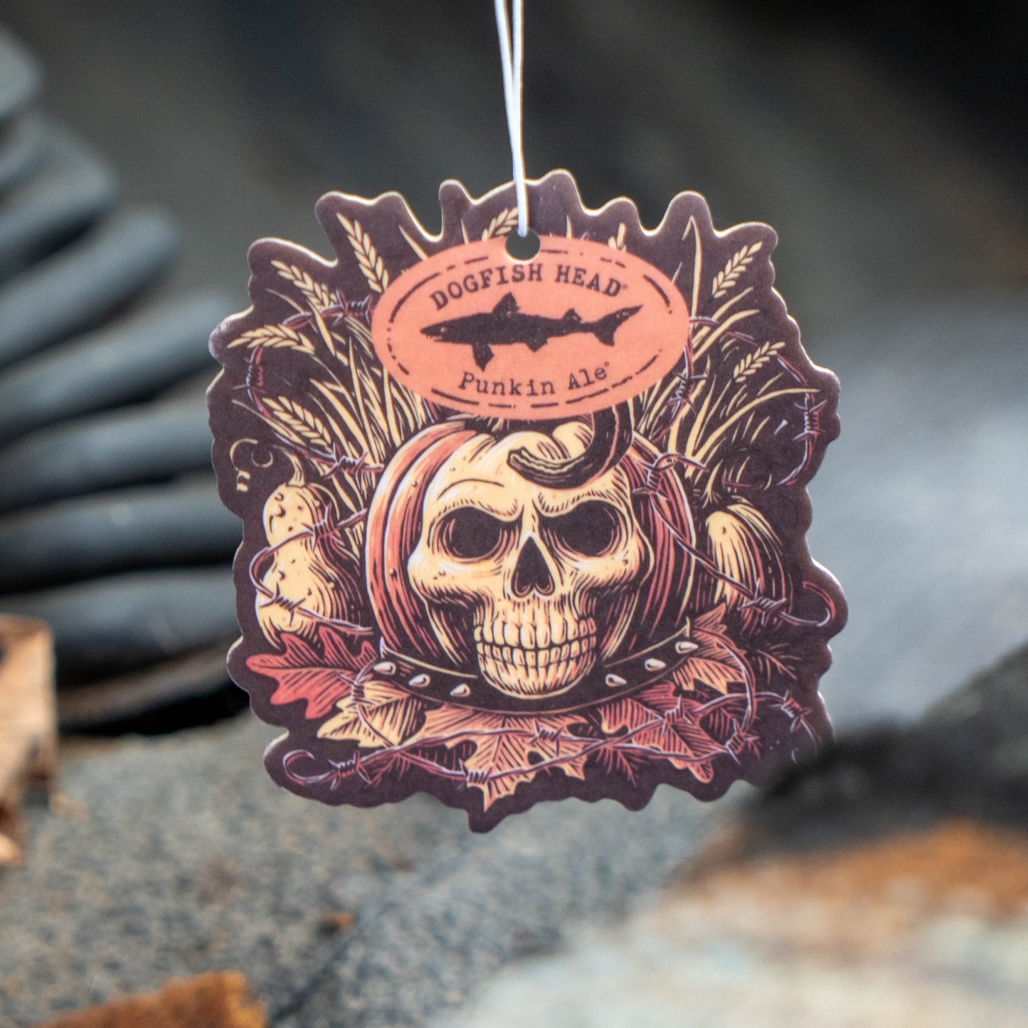 A die-cut hanging air freshener or tag featuring a skull, corn, and autumn leaves design with the text 'DOGFISH HEAD Punkin Ale'.