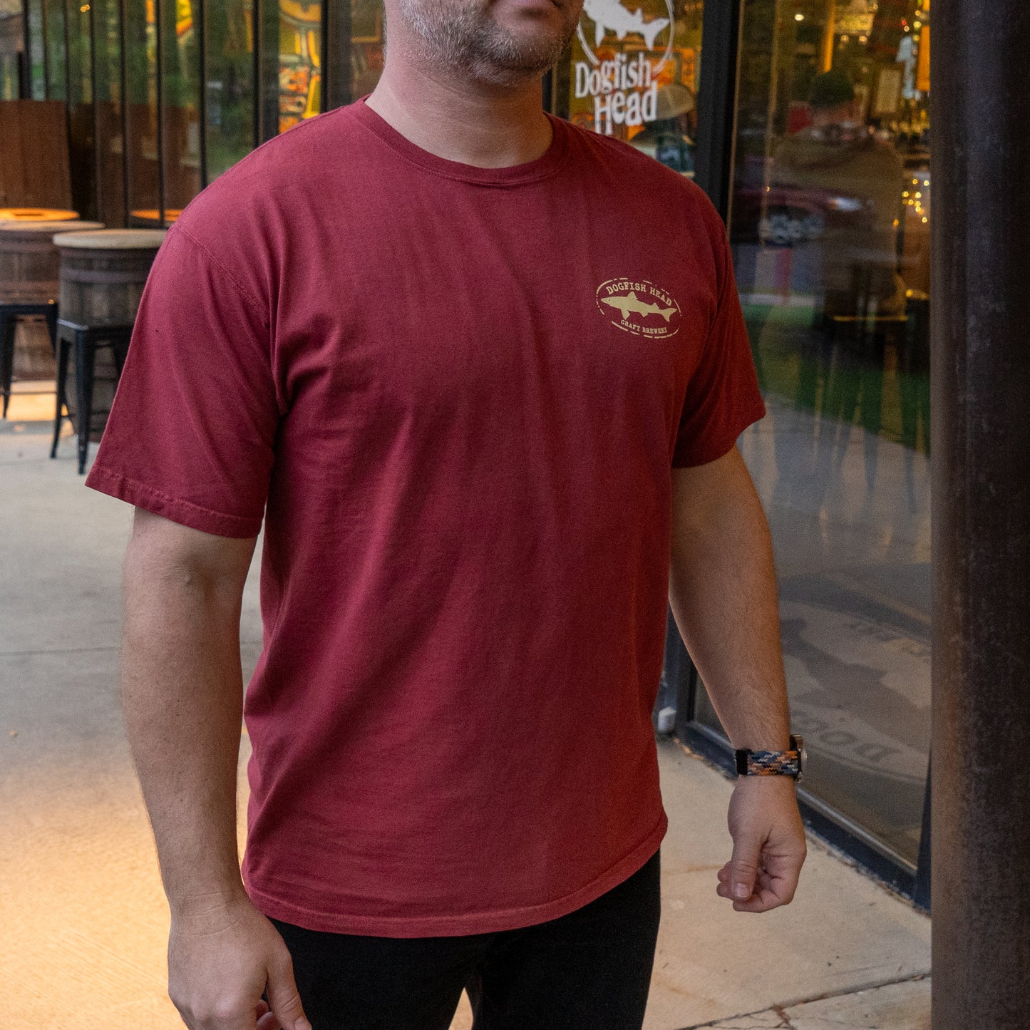 Person wearing a red t-shirt with a logo in an outdoor setting