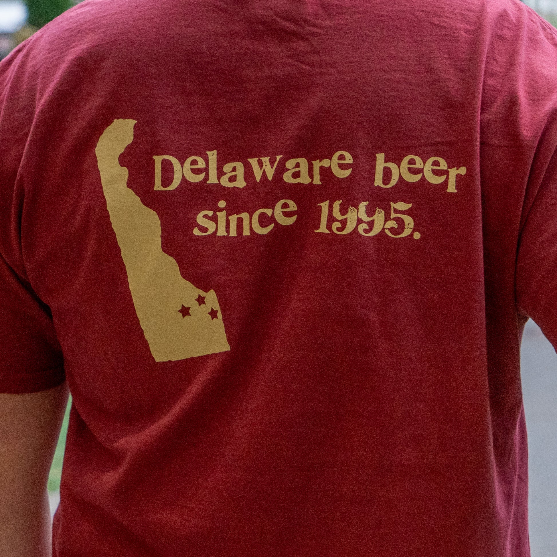 Person wearing a red t-shirt with 'Delaware beer since 1945' text on the back.