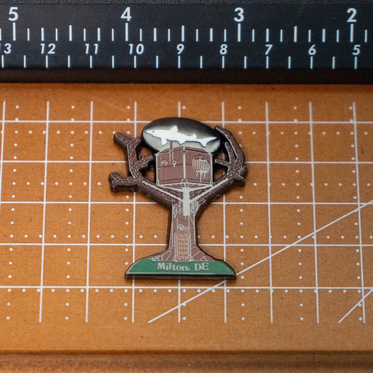 Treehouse Enamel Magnet shaped like a treehouse with a shark silhouette in the sky, labeled Milton DE at the base.